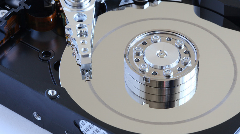 The inside of a hard drive, a metal disk and a metal arm.