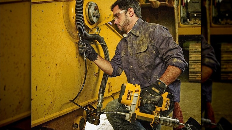 Man using a grease gun to lubricate machinery