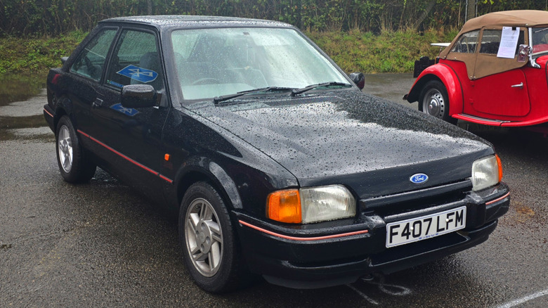 1989 Ford Escort in black, parked and covered in raindrops