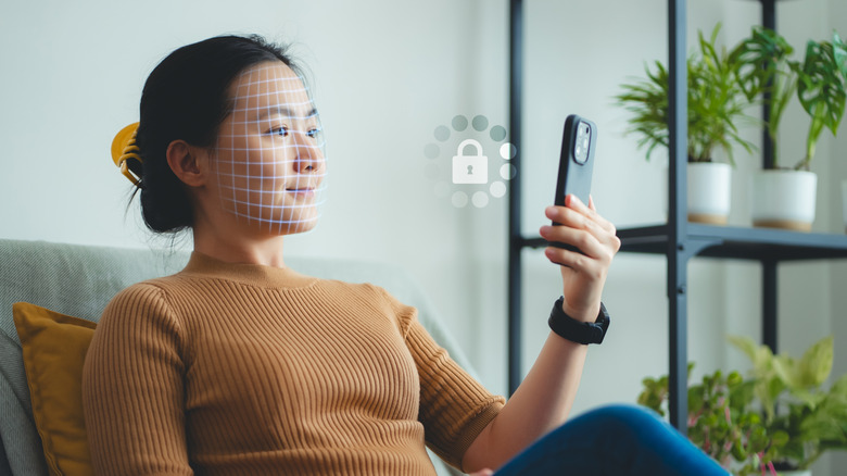 A woman scanning her face using Face ID on her iPhone to unlock it