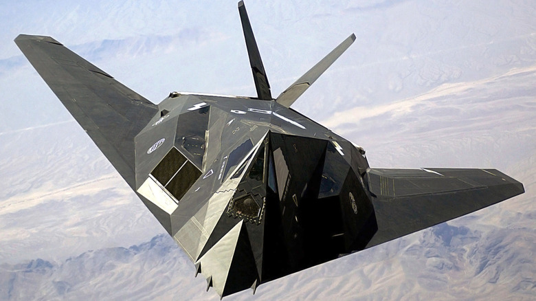F-117A Nighthawk stealth fighter jet seen from in front and slightly above on patrol above desert mountains