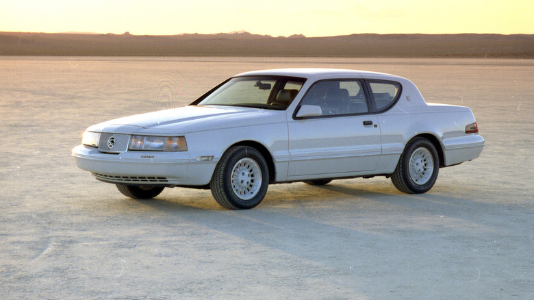 White 1988 Mercury Cougar XR-7 couple seen from left front parked on a salt flat at twilight