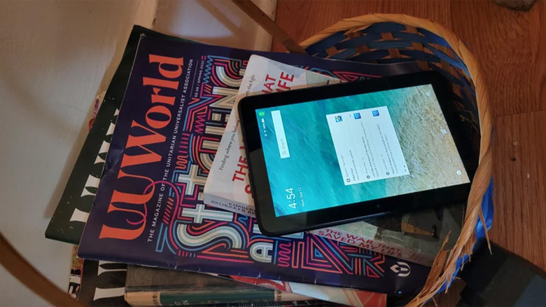 A photo of the Amazon Fire 7 Tablet in a basket with magazines