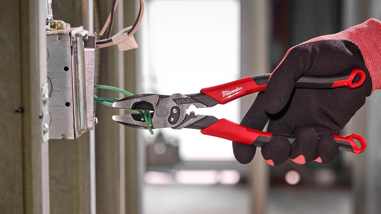 A pair of Milwaukee pliers being used to cut wires.