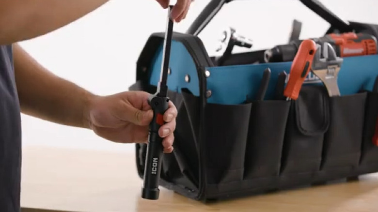 Person adjusting work light next to a tool bag