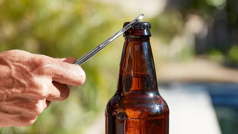 Pittsburgh wrench/bottle opener being used on a brown glass bottle outside on a sunny day