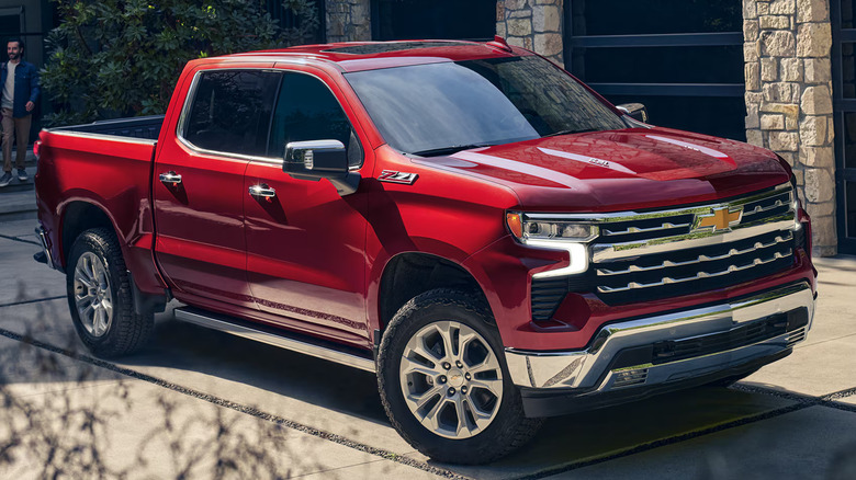 A family walking toward a red Chevy Silverado