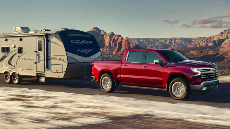 The Chevy Silverado hauling a trailer across a road in the desert