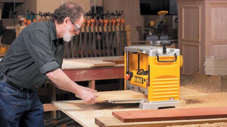 person using planer in a wood shop