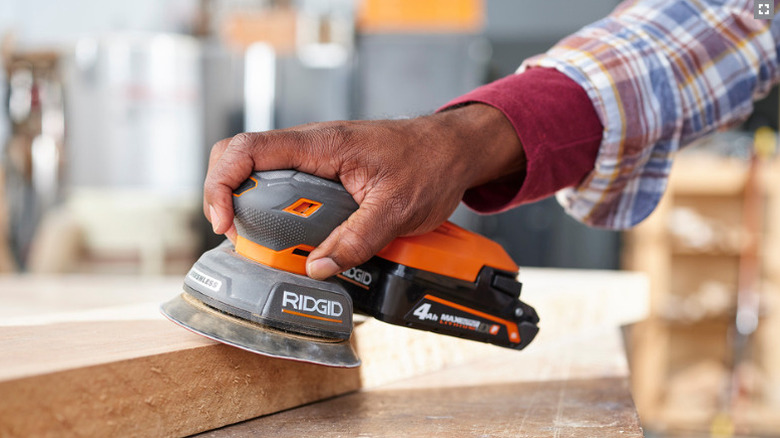 person using sander on wood