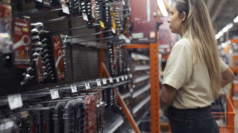 A woman stands in front of a lineup of tools inside a store