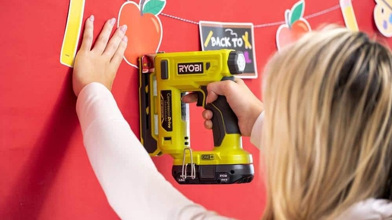 A person stapling pictures on a wall.
