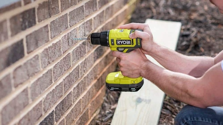 A hammer drill being used on some bricks.