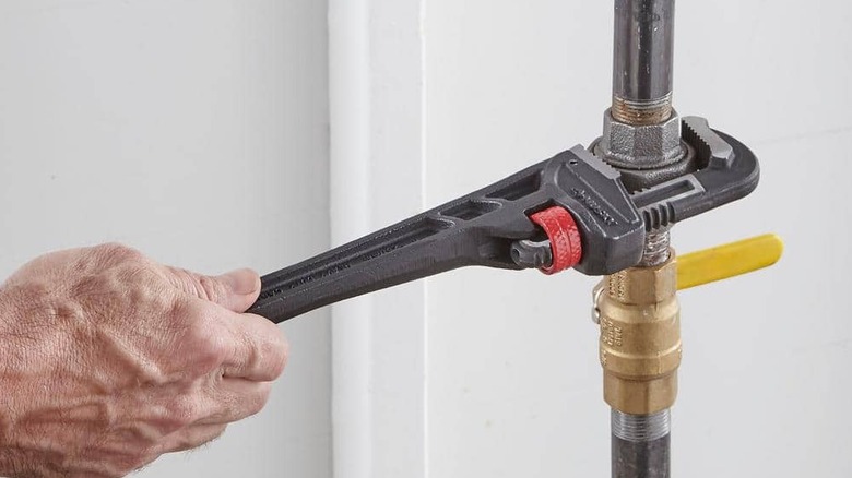 A pipe wrench being used on a pipe.