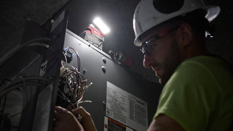 A light pointed on a person working on wires.