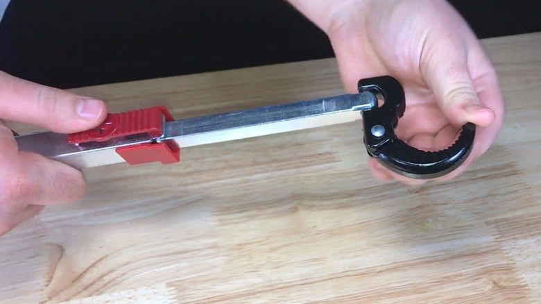 A basin wrench being opened by a hand.