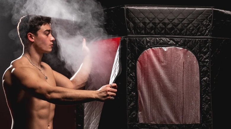 Man entering tall black stall emitting steam and red light