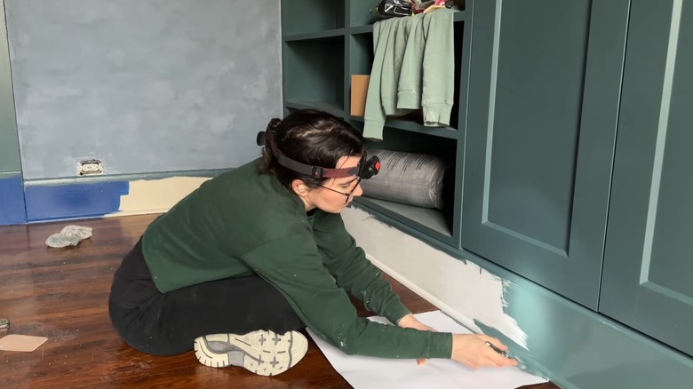 Renee from Renee Renovates painting baseboards on a built-in unit