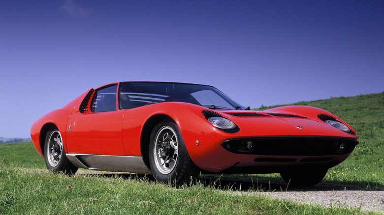 Red Lamborghini Miura parked on a dirt road