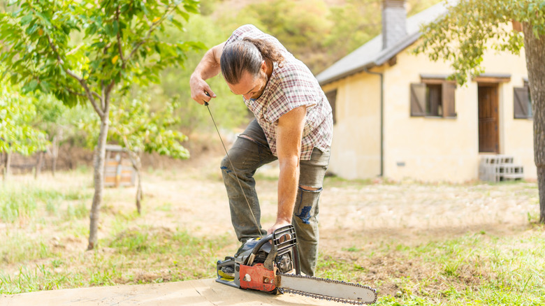 man starting a large chainsaw
