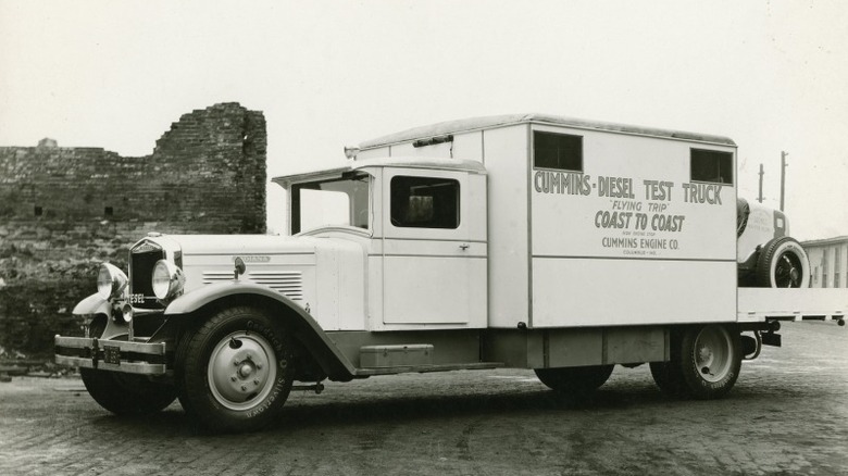 Vintage Cummins Diesel Test Truck parked on a cobblestone street, with lettering that reads "Cummins Diesel Test Truck - Flying Trip Coast to Coast - Cummins Engine Co."