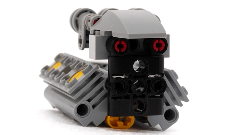 A LEGO Technic V8 engine model built with grey, black, red, and yellow pieces.