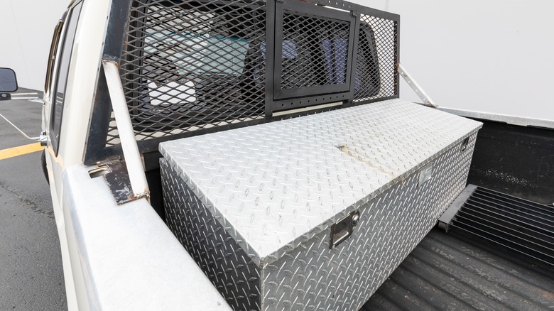 A white pickup truck with a metal tool box on its bed.
