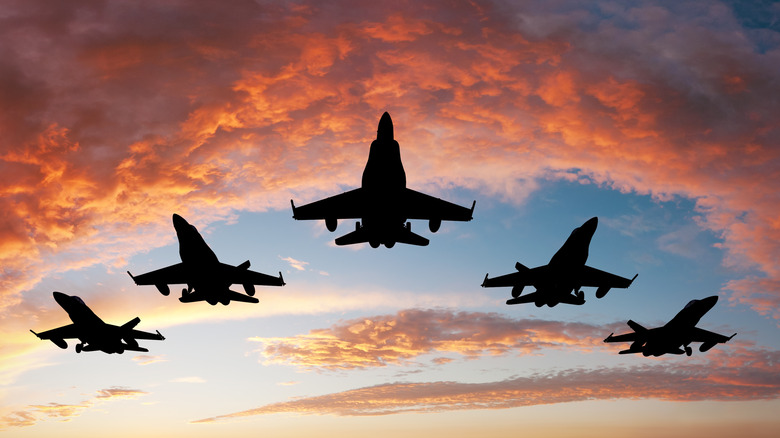 Military aircraft flying amidst sunset