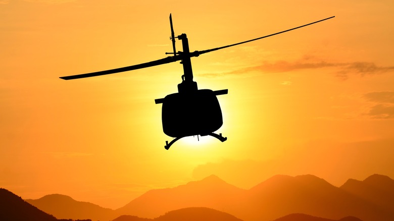 A helicopter flying into the sunset