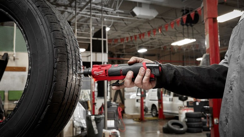 Man using a tire buffer on a tire in an automotive garage.