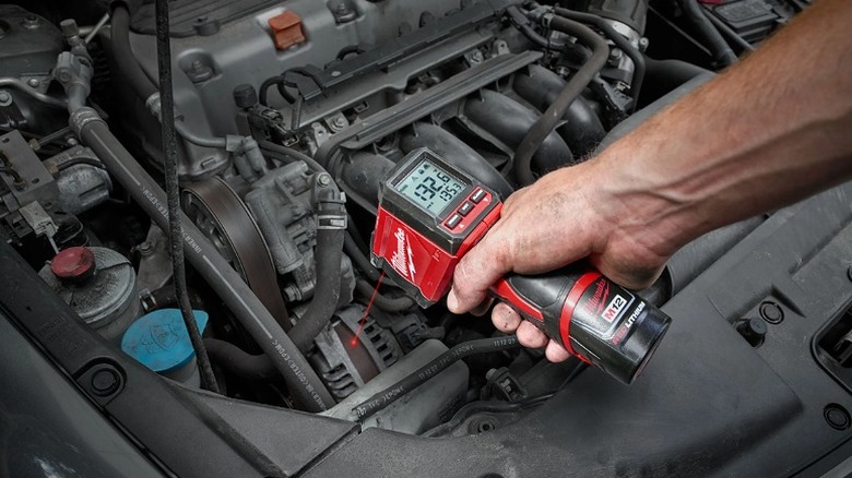 Man pointing the temp gun to a car's engine.
