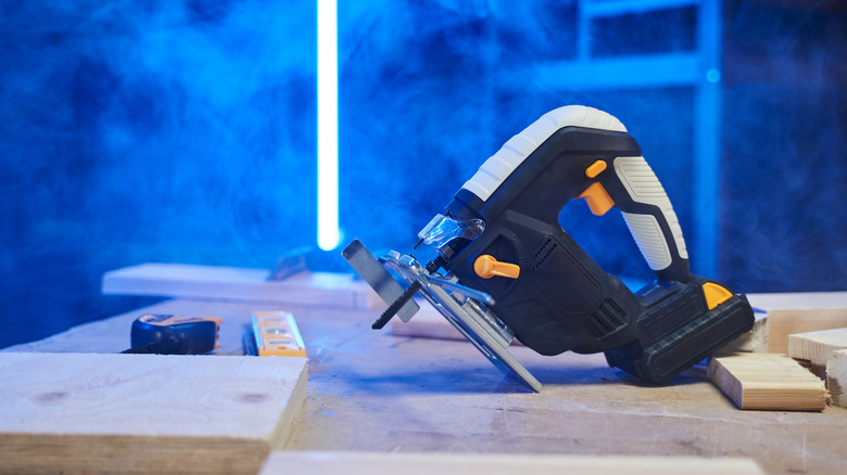 A jigsaw sitting on a table under blue light with smoke all around.