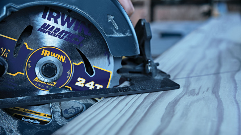Close-up of an Irwin Marathon 24-tooth circular saw blade mounted on a power saw, actively cutting through a piece of wood.