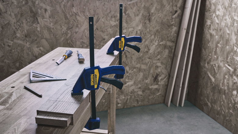 Woodworking setup with two Irwin Quick-Grip clamps securing a wooden board to a workbench.