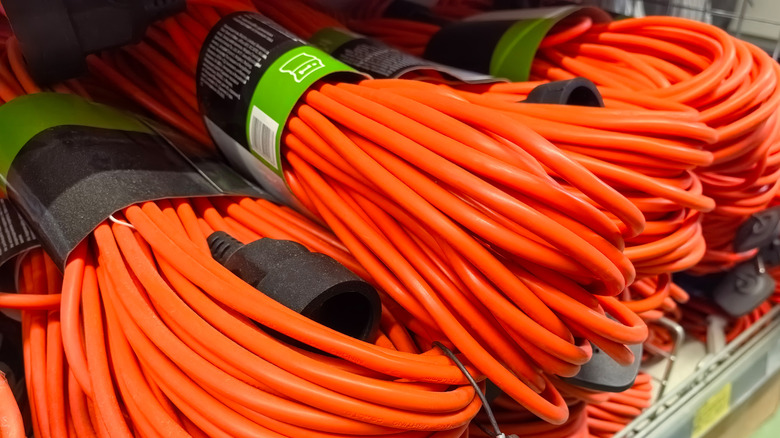 A close-up of a stack of bright orange extension cords on a store shelf.