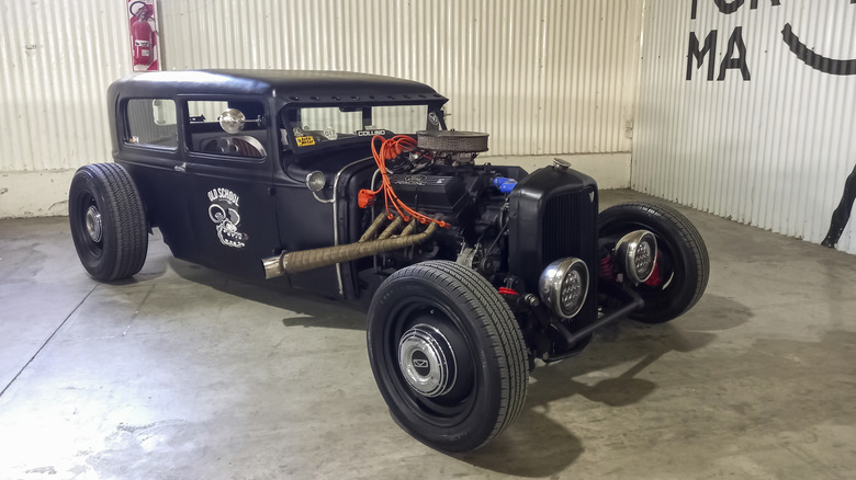 Black hot rod with exposed headers parked in garage