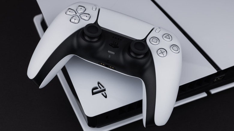 A DualSense controller resting atop a white PS5 console