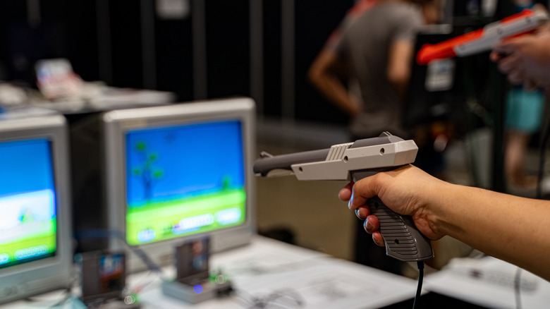 A person's hand holding an an NES Zapper, pointing it at a CRT TV