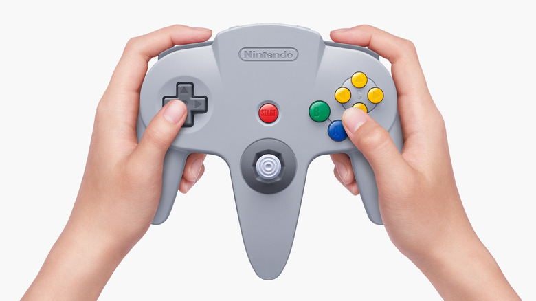A pair of hands holding the Nintendo 64 controller against a white background