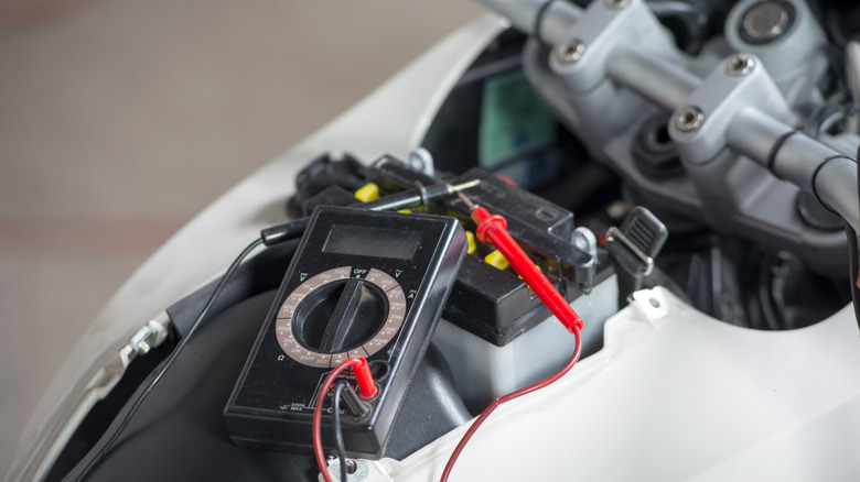 A motorcycle battery being tested by a technician
