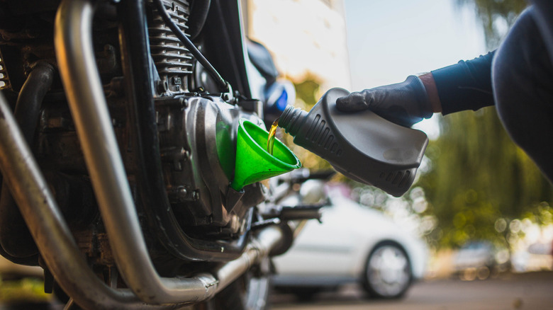 Person pouring engine oil in a motorcycle with the help of a funnel