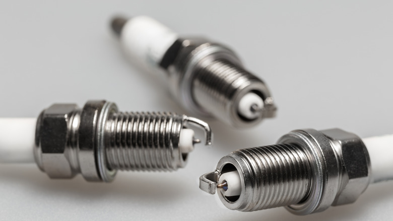 Closeup of three motorcycle spark plugs against a white background