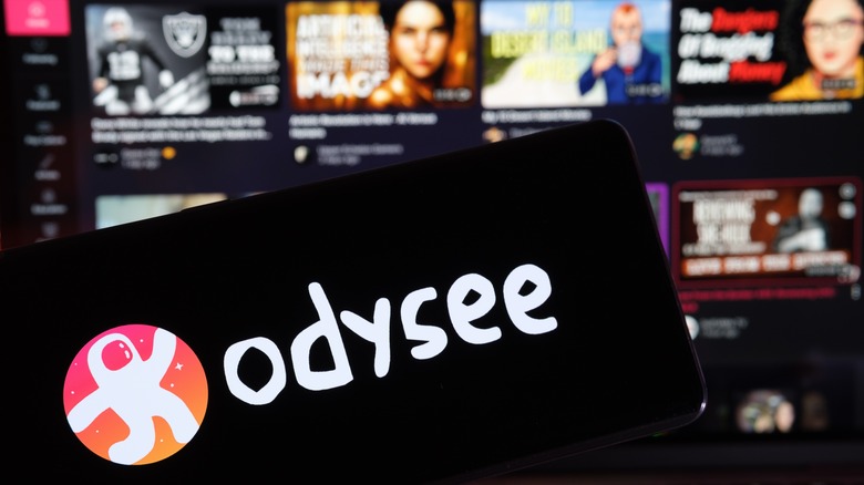 Odysee logo, blurred website background