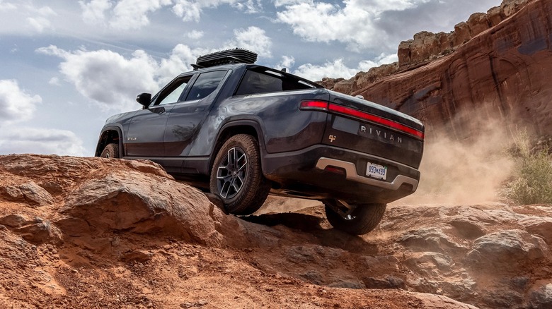Rear view of Rivian R1T driving over rocks