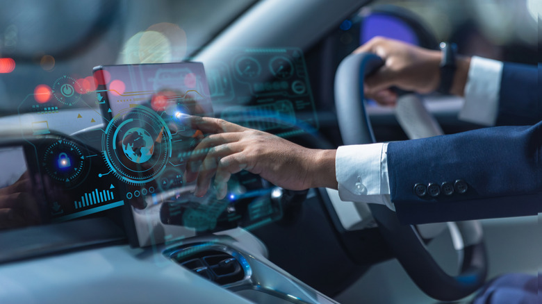 Set of hands touching a tech-style overlay in a car