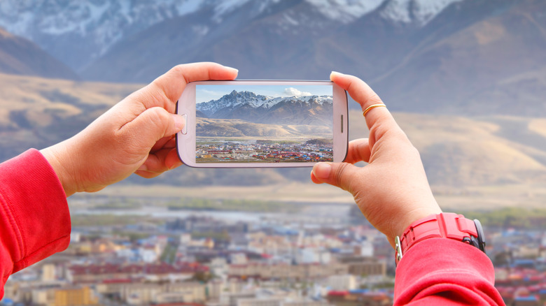 Smartphone photographing village beneath mountains