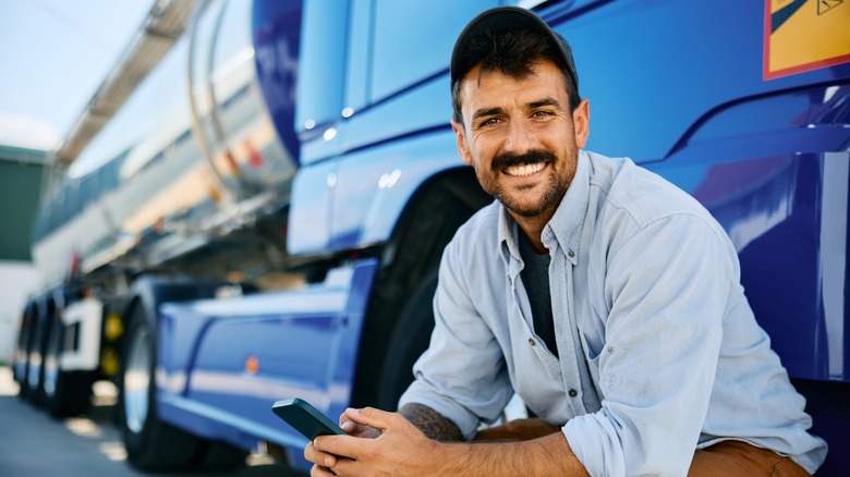 Happy truck driver texting on a mobile phone
