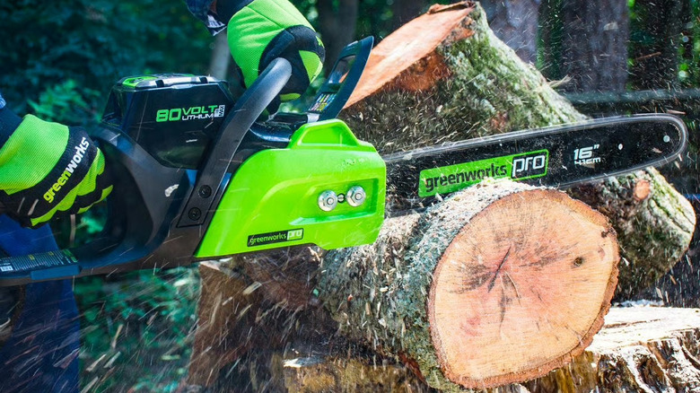 Person cutting through log with chainsaw