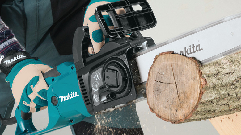 Person using chainsaw on log