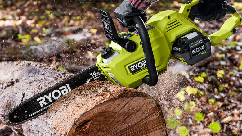 Person cutting through log with chainsaw